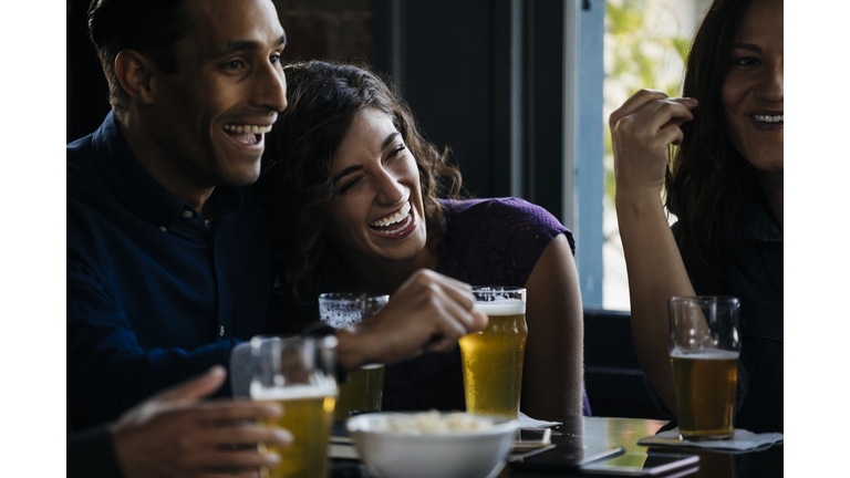 Friends laughing over drinks in bar