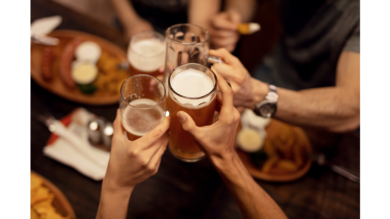 Close up of friends toasting with beer and having fun in a pub.