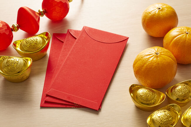 Chinese New Year and Lunar New Year celebrations with gold bar Ang Pao red envelope orange and hot tea. (with the character 