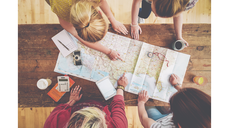 Caucasian women planning trip with map on wooden table