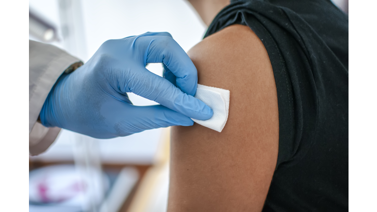 Doctor disinfects skin of patient before vaccination