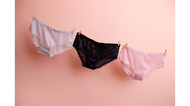 colorful clean women's panties hang on a rope. on a pink isolated background