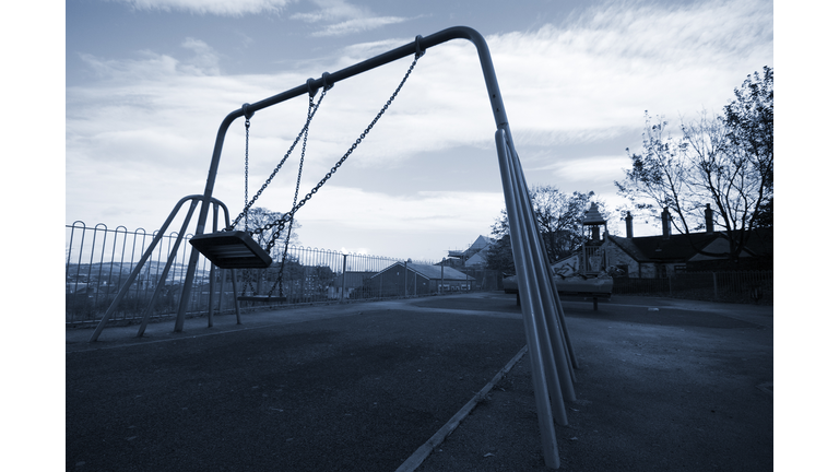 A grayscale playground swing in mid swing