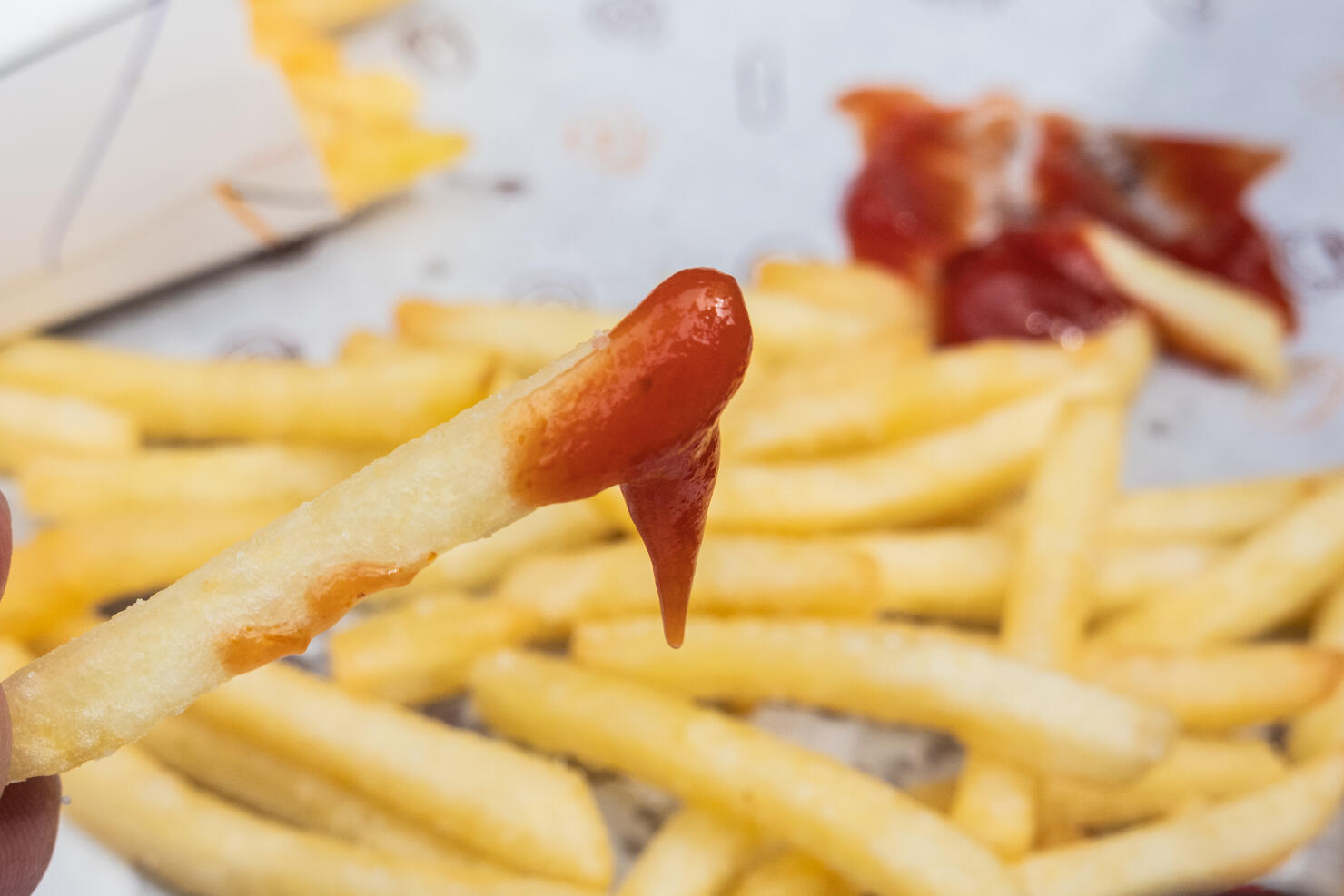 A person eating french fries with ketchup.
