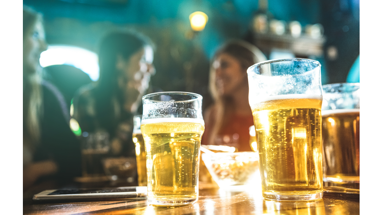 Happy girlfriends women group drinking beer at brewery bar restaurant - Friendship concept with young female friends enjoying time and having genuine fun at cool vintage pub - Focus on beer glasses