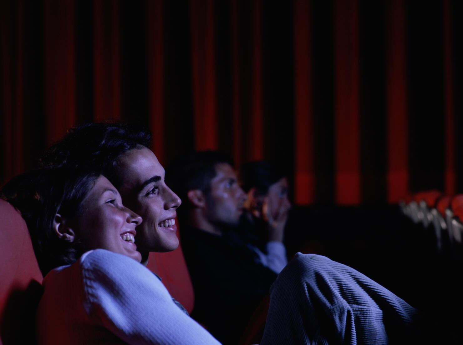 Teenage couple (16-18) laughing in auditorium, side view