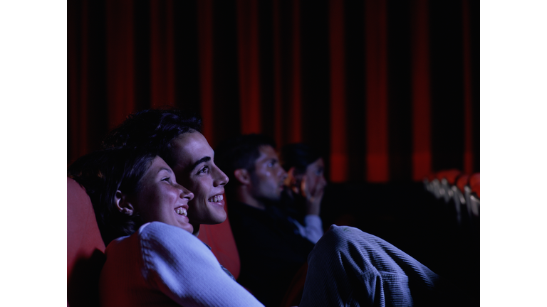 Teenage couple (16-18) laughing in auditorium, side view