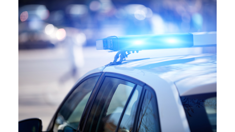 Police car with blue lights on the crime scene in traffic urban environment.