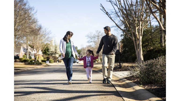 Family of three walking in suburban neighborhood