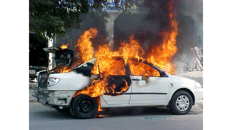 Flames erupt from a burning car after a