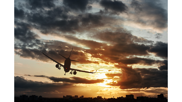 Silhouette of a business plane flying over the city and making an emergency landing at night