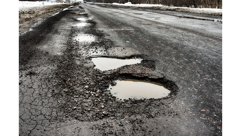 old highway with holes and snow. Landscape road potholes in cloudy winter weather. concept absence of timely repair of highway.