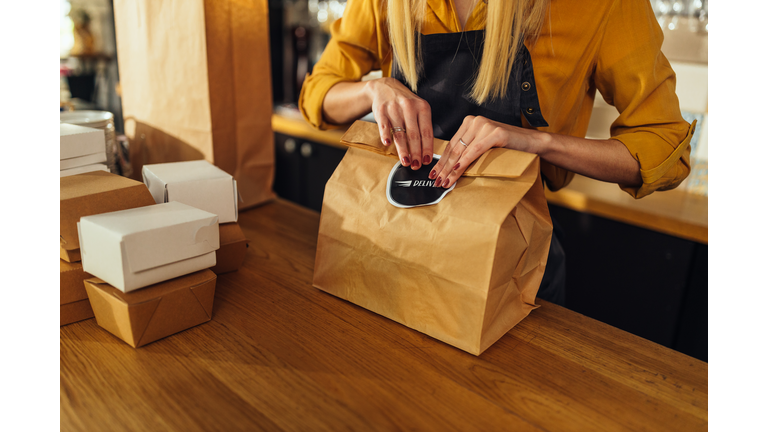 Close up of woman packing food for delivery