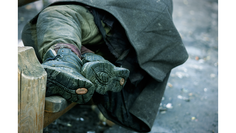 A photograph of a homeless mans legs on a bench