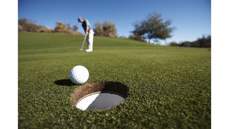 Male golfer putting on golf course