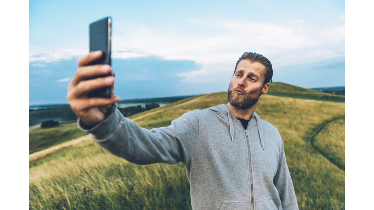 Hipster with beard makes a duck face and shoots a selfie