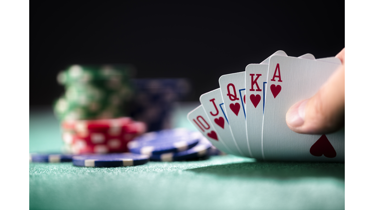 Playing poker in a casino holding winning royal flush hand of cards