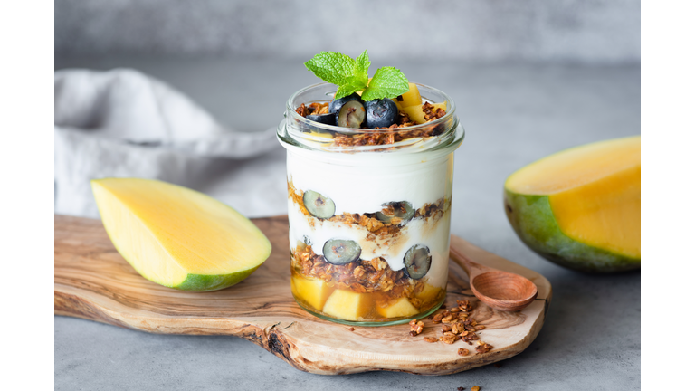 Breakfast yogurt parfait with granola, mango, berries in jar