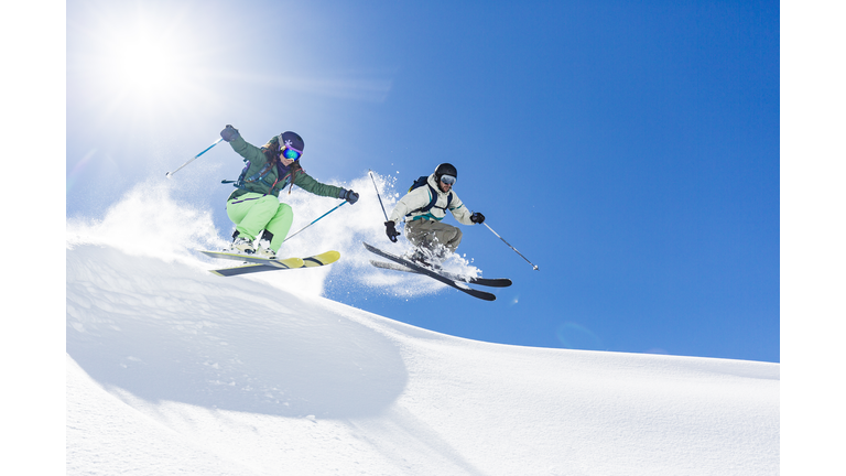 Woman and man skiing and jumping