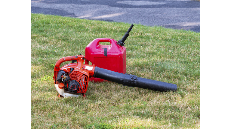 Red leaf blower and gas can on a residential lawn