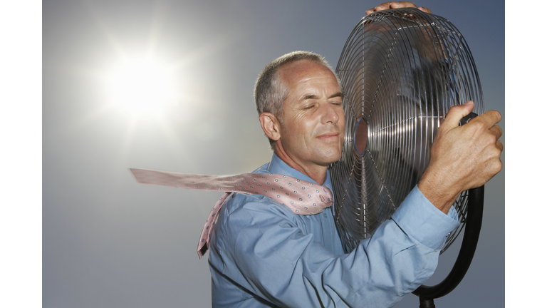 Hot, Relieved Businessman Holding an Electric Fan