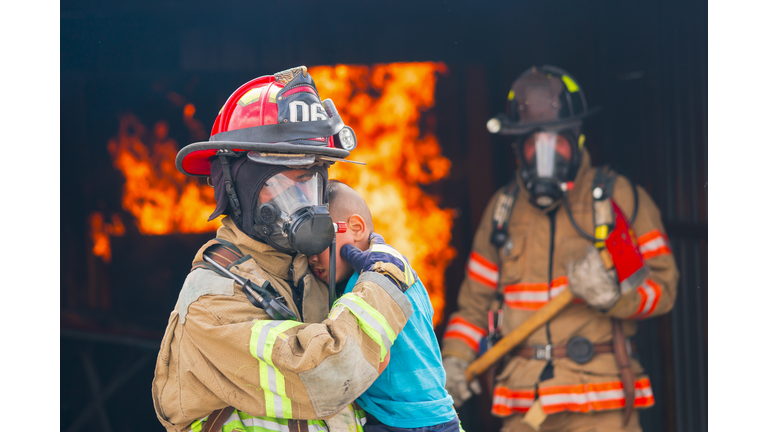 Firefighter saving boy in burning house .