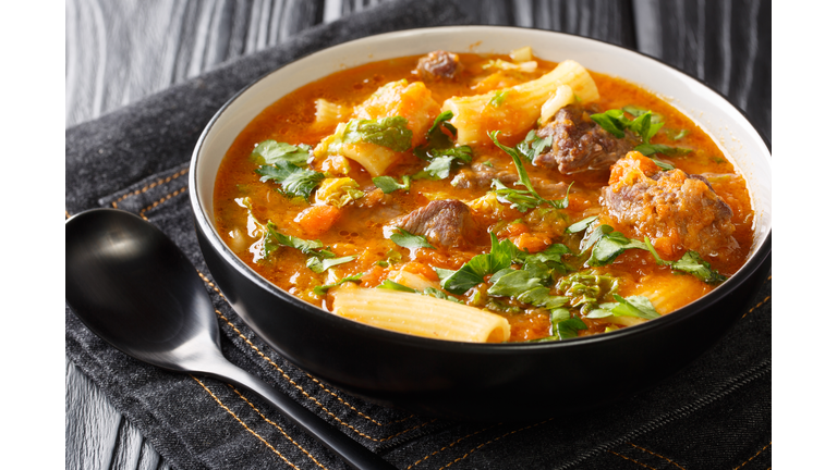 Soup Joumou or Haitian Beef and Pumpkin Soup is a famous mildly spicy soup prepared with beef and vegetables and also rigatoni pasta closeup in the plate. Horizontal