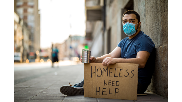 Homeless man sitting and asking for help while holding cardboard