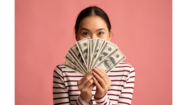 Big Profit. Happy Young Asian Woman Covering Face With Dollar Cash Fan