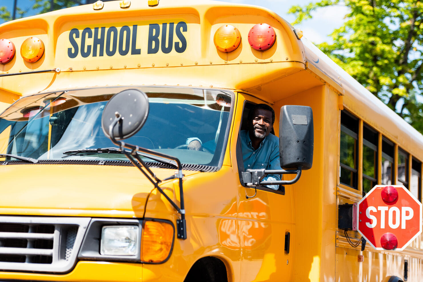 handsome senior school bus driver looking at camera through window