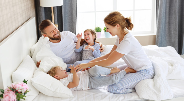 happy family mother, father and children laughing, playing and tickles in bed   at home