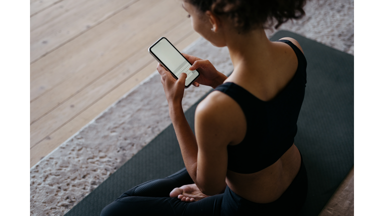 Adult african american athletic woman using modern smartphone