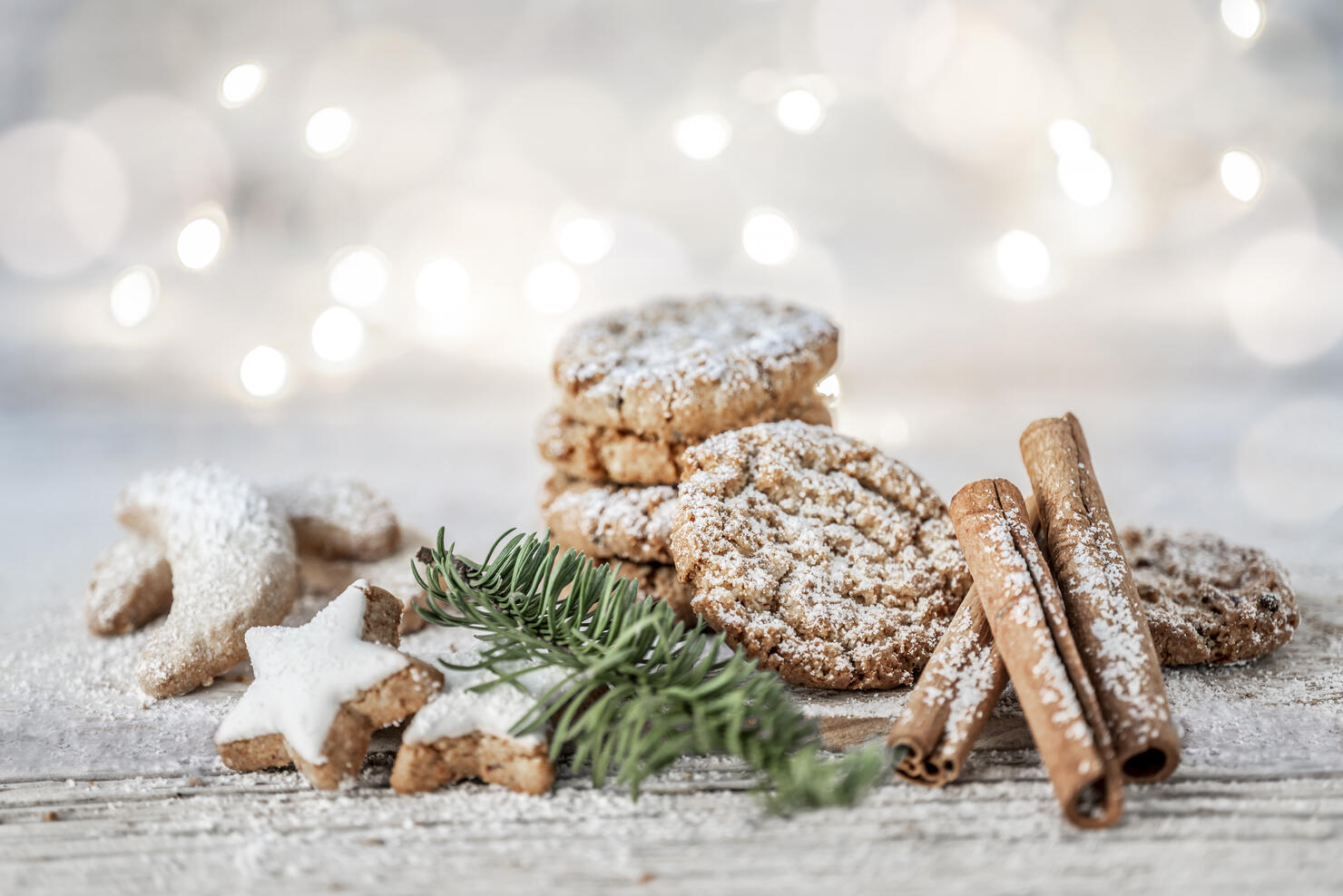 Vegan oatmeal cookies with powdered sugar, cinnamon sticks and cinnamon stars on a wooden table at christmas.