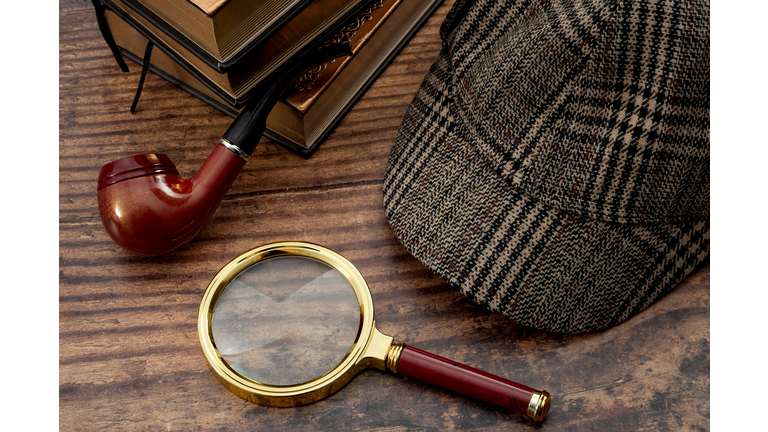 Literary fiction, police inspector, investigate crime and mystery story conceptual idea with sherlock holmes detective hat, smoking pipe, retro magnifying glass and book isolated on wood table top