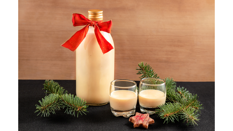 Homemade eggnog in bottle and two glasses with Christmas cookies