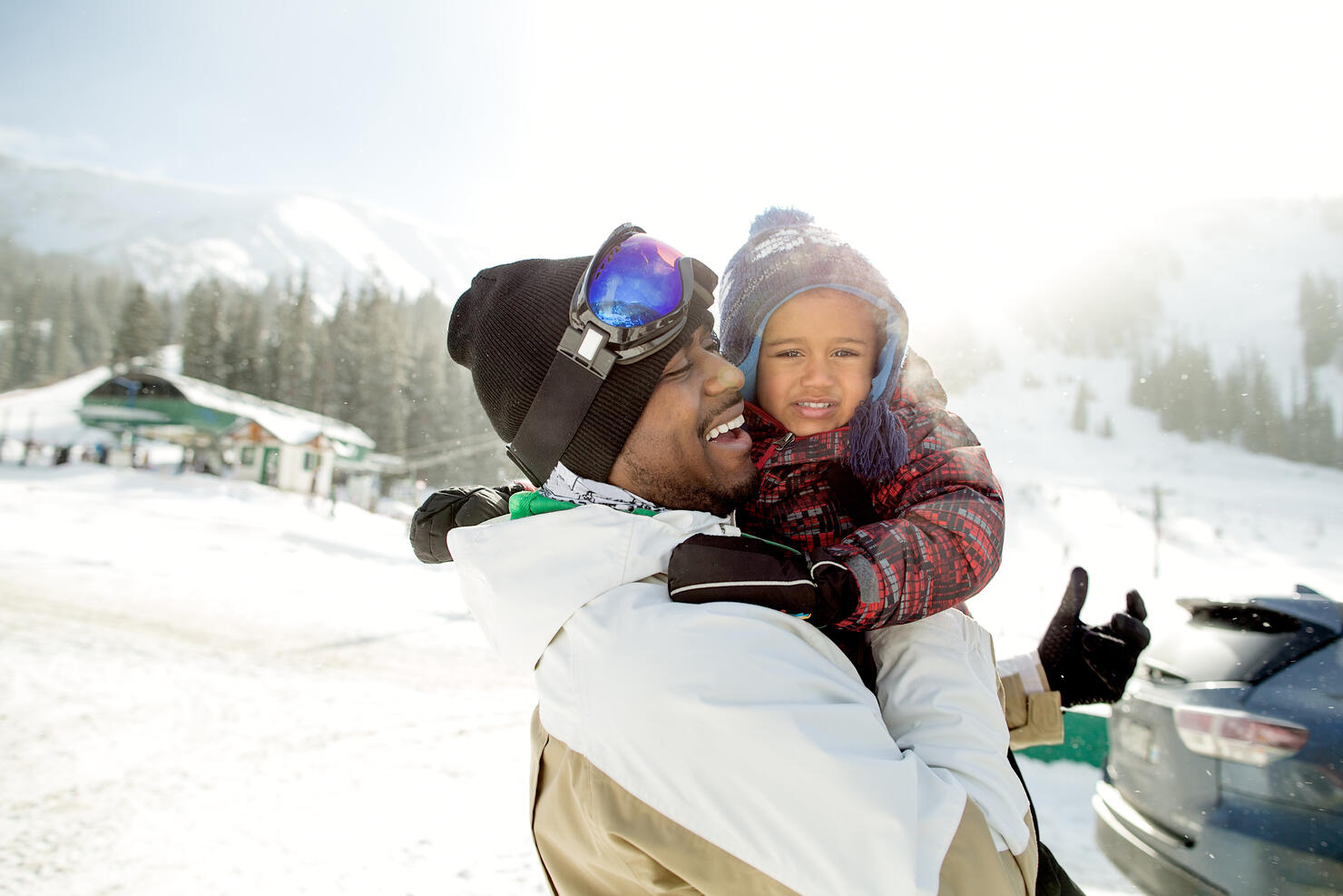 Happy multi-ethnic father and son at a ski resort getting ready to go skiing.