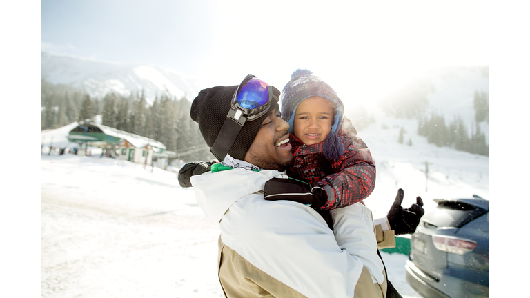 Happy multi-ethnic father and son at a ski resort getting ready to go skiing.