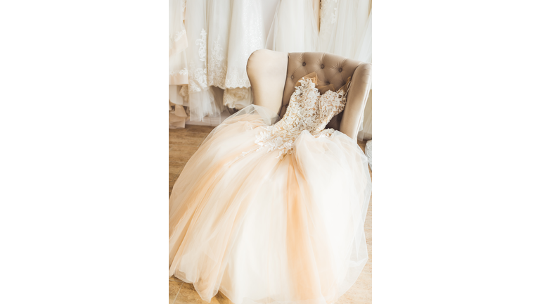 Lace wedding dress on chair in wedding salon