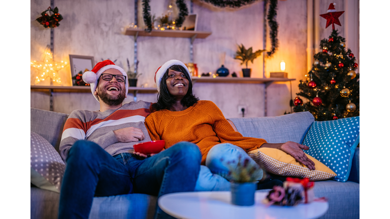 Young couple watching tv at home at Christmas