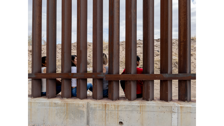 Group of Mexican People looking through the International Border Wall between Chihuahua Mexico and Texas, USA