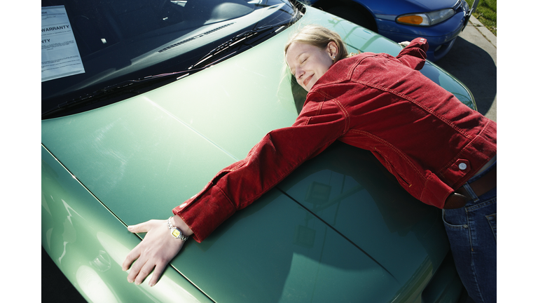 Woman hugging hood of car, elevated view