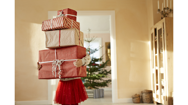 Girl holding tall stack of christmas presents