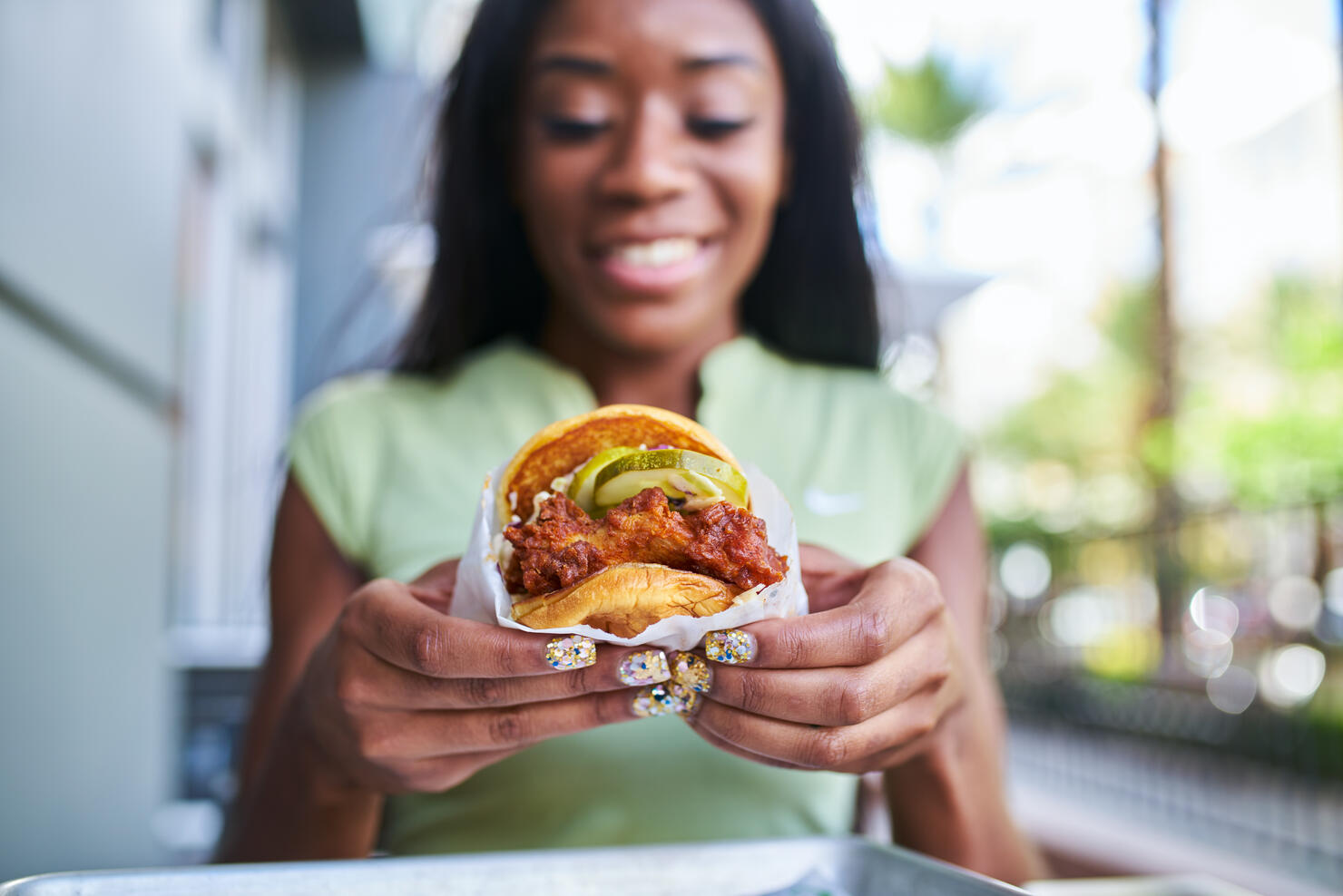 african american woman holding fast food style crispy fried chicken sandwich