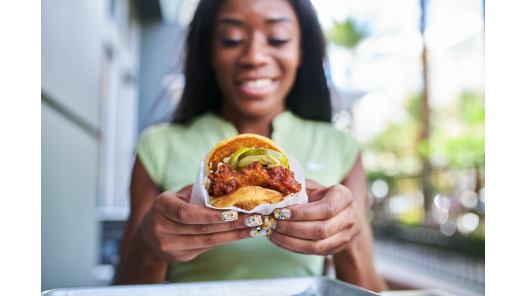 african american woman holding fast food style crispy fried chicken sandwich