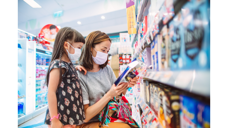 Mom & daughter with protective face masks shopping for daily necessities in supermarket