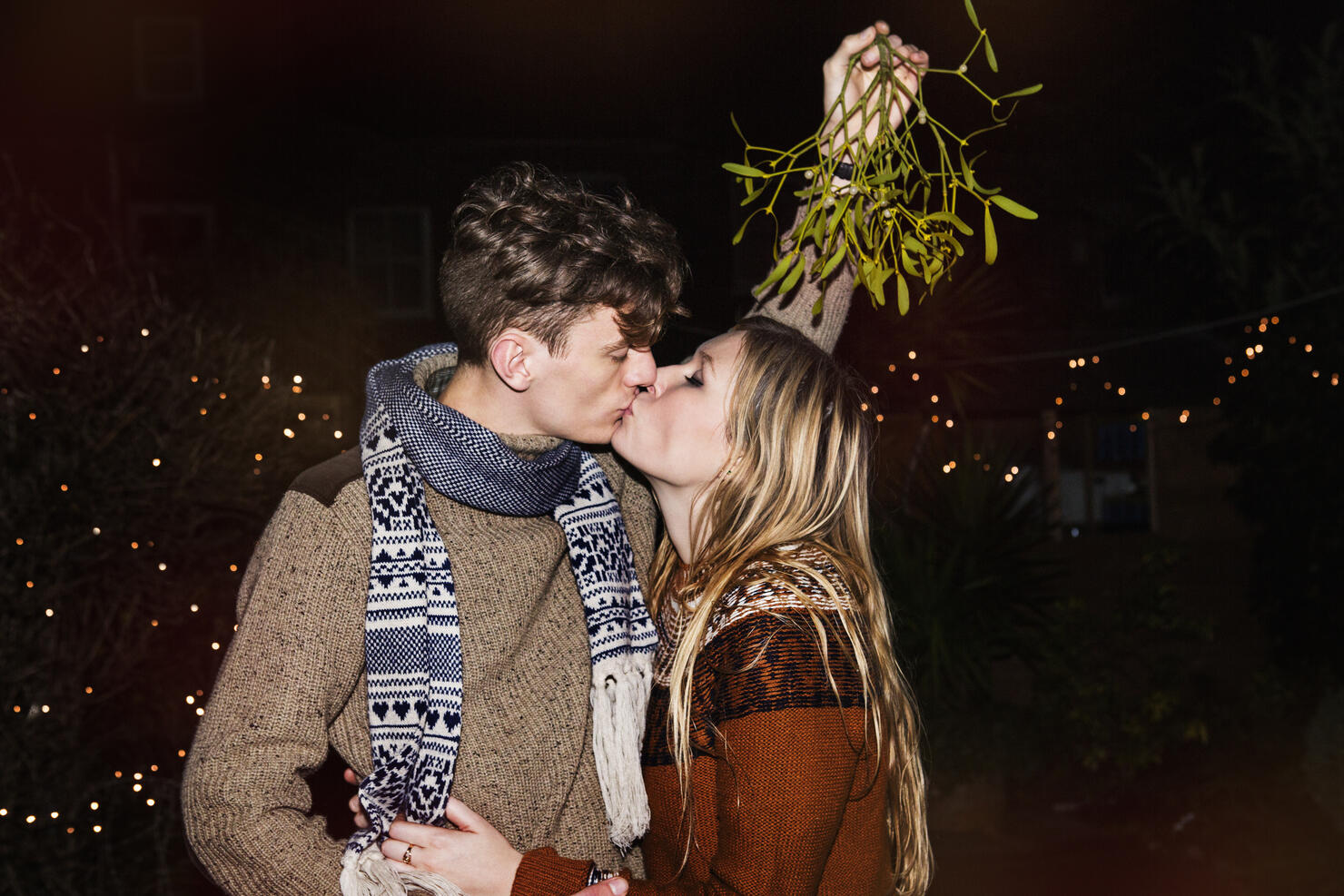 Couple kissing outdoors under mistletoe
