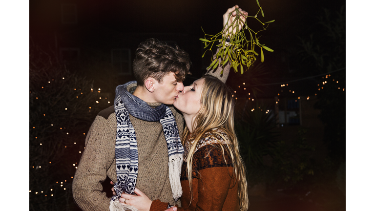 Couple kissing outdoors under mistletoe