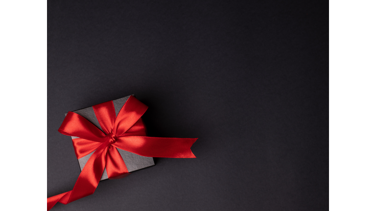 Gift box with red bow on black background