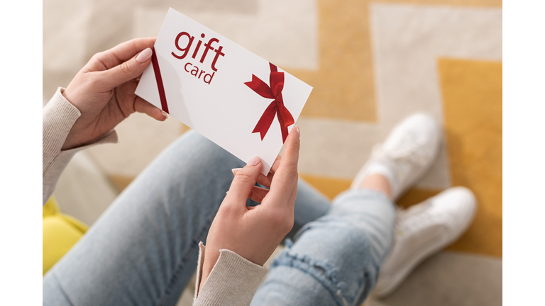 Cropped view of girl holding gift card with red bow