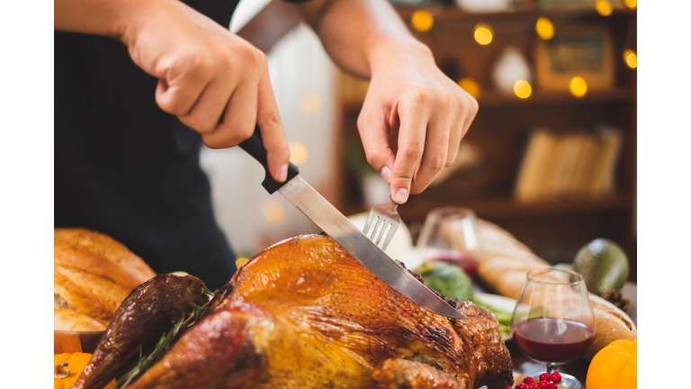 Close up hand with knife slice turkey on table happy Thanksgiving dinner party with family